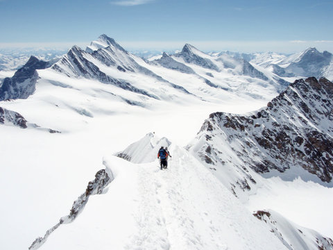 mountain guide and client descending a high alpine peak with a gigantic panorama of the Swiss Alps