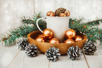 Fototapeta na wymiar Christmas composition with white cup,fir banch,cones and golden balls.New Year.Wooden table.