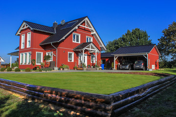 Fototapeta na wymiar Rotes Schwedenhaus mit Carport und Garten
