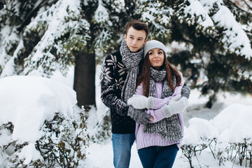 Happy stylish couple in winter pine forest on Christmas