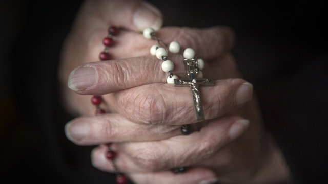 Old Hands Praying And Holding A Rosary