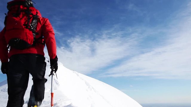 Mountaineer arrive at the top of a snowy peak in winter season. Concepts: determination, courage, effort, self-realization.