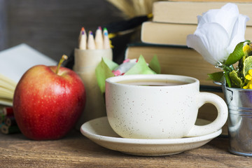 books, coffee and apple, pencils and some other school supplies on a rustic wooden school desk. selective focus image 