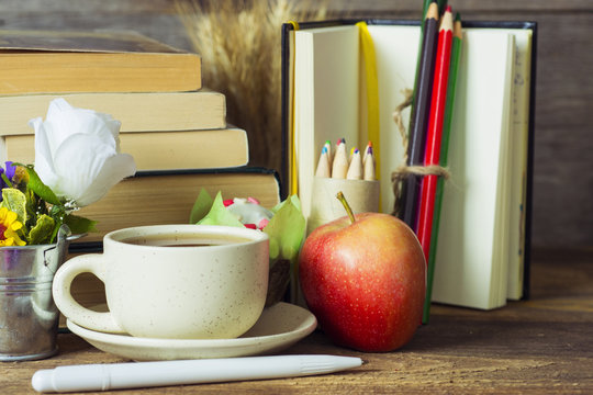 books, coffee and apple, pencils and some other school supplies on a rustic wooden school desk. selective focus image 