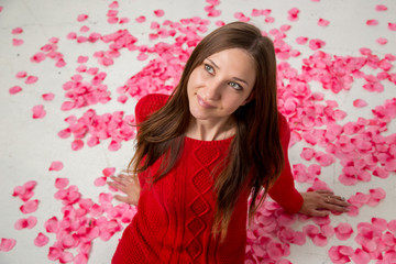 Obraz na płótnie Canvas Young happy woman in red sweater in rose petals
