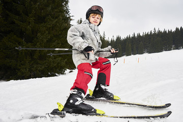 Child boy skiing in mountains. Active teenager kid with safety helmet and goggles. Winter sport for...