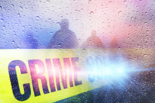 Police crime scene with lights, police tape and raindrops with silhouettes in the background