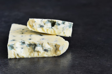 Slice of blue cheese on a black background