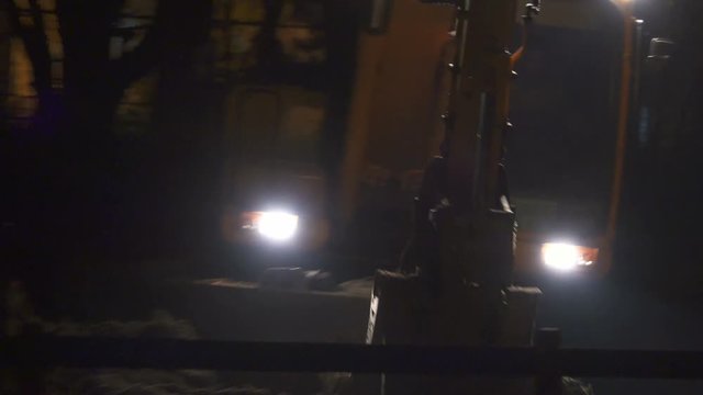Excavator aligns ground at night with the lights on