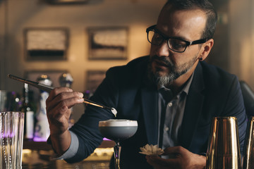 Barman is making cocktail at night club.