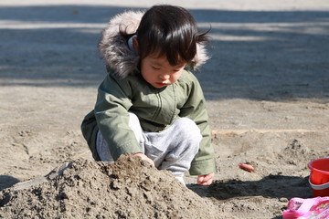 砂場で遊ぶ二歳児