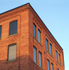 business building corner, red brick in sunshine windows on blue sky