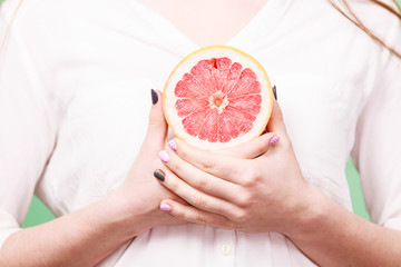 Woman holds half of grapefruit citrus fruit in hand