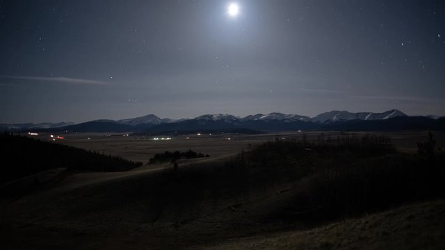 Moonset and rural traffic with Snow capped mountains timelapse