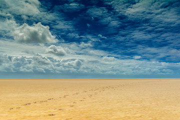 Fototapeta na wymiar Strand mit weitem Horizont, Wolkenmeer und Fußspuren