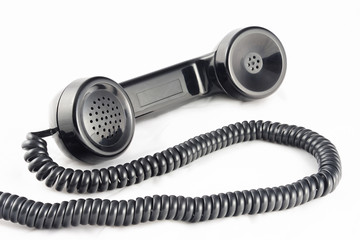 Outdated telephone handset with black with coil cable. Horizontal.