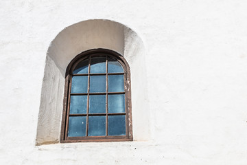 Spanish revival style arched window on white stucco wall.