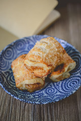 Fresh puff pastries with blank book on wooden background