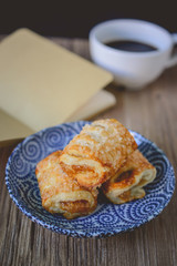Fresh puff pastries and coffee cup with blank book on wooden bac