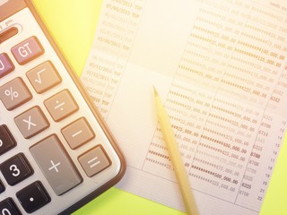 Business or finance background concept : Calculator, pencil and savings account passbook on yellow...