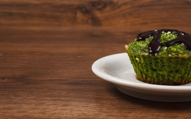 Fresh muffin with spinach, desiccated coconut and chocolate glaze, delicious healthy dessert, copy space for text