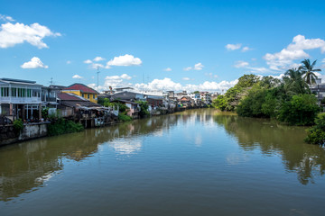 Urban canal village under blue sky and clouds, Thailand
