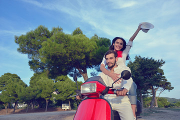 Beautiful young couple in love enjoying and having fun riding on a scooter
