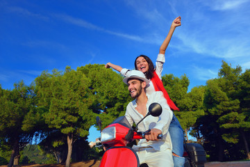 Beautiful young couple in love enjoying and having fun riding on a scooter