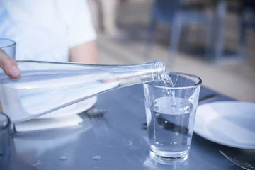 Fototapeten Pouring Distilled water into a clear glass at a restaurant © Brocreative