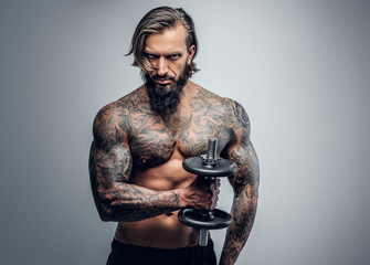 Fototapeta premium Tattooed bearded male holds dumbbel.