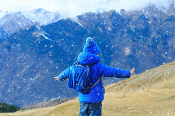 little boy enjoy travel in winter mountains