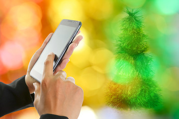 Woman hand holding and touch screen smart phone, over Christmas decorations.