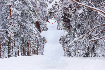 Snowman on the background of snow-covered pine forest