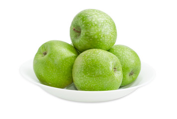 Several green apples on a white dish closeup