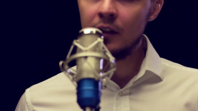 Young attractive male singer coming to microphone and start singing