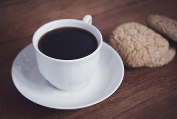 fresh cup of coffee and biscuits for breakfast on a wooden table