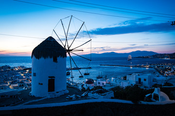 Windmill on Mykonos overlooking the town and port at dusk - obrazy, fototapety, plakaty