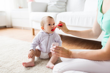 mother with spoon feeding little baby at home