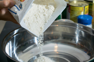 close up of pouring the flour in to the stainleass blow preparation step to cooking some food that by flour