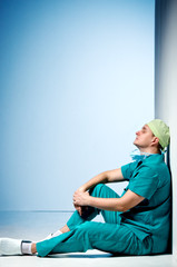Tired doctor sit on the floor in the hallway of the hospital. - 127275903