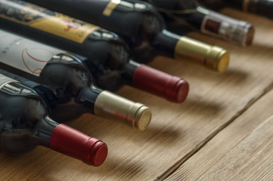 Row of red dry wine bottles  on wooden background. Low depth of field. 
