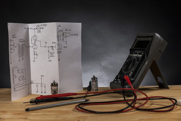 Handwritten electronics schematic diagram, with audio vacuum tubes and multimeter. Black background