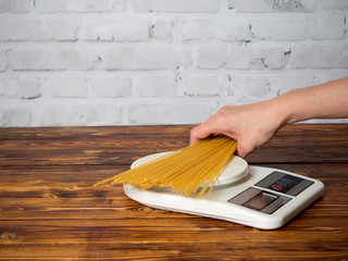 Woman weighing spaghetti on the kitchen scales