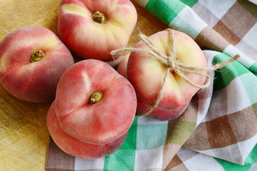 Dough nut peaches also known as Saturn peach with hemp rope  on wooden board.
Benefits of Dough nut peaches. 
