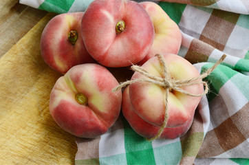 Dough nut peaches also known as Saturn peach with hemp rope  on wooden board.
Benefits of Dough...