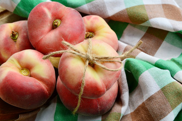 Dough nut peaches also known as Saturn peach with hemp rope  on wooden board.
Benefits of Dough...