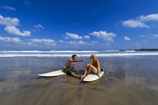 Male and Female Surfers in Conversation on Beach