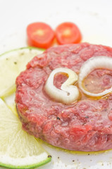 Steak tartare closeup  with lemon slices on white plate