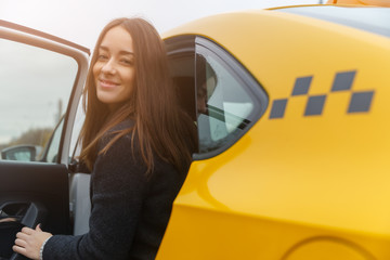 Smiling young brunette woman sits in yellow taxi