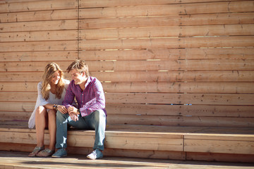 Portrait of smiling young and beautiful couple seated on a bench